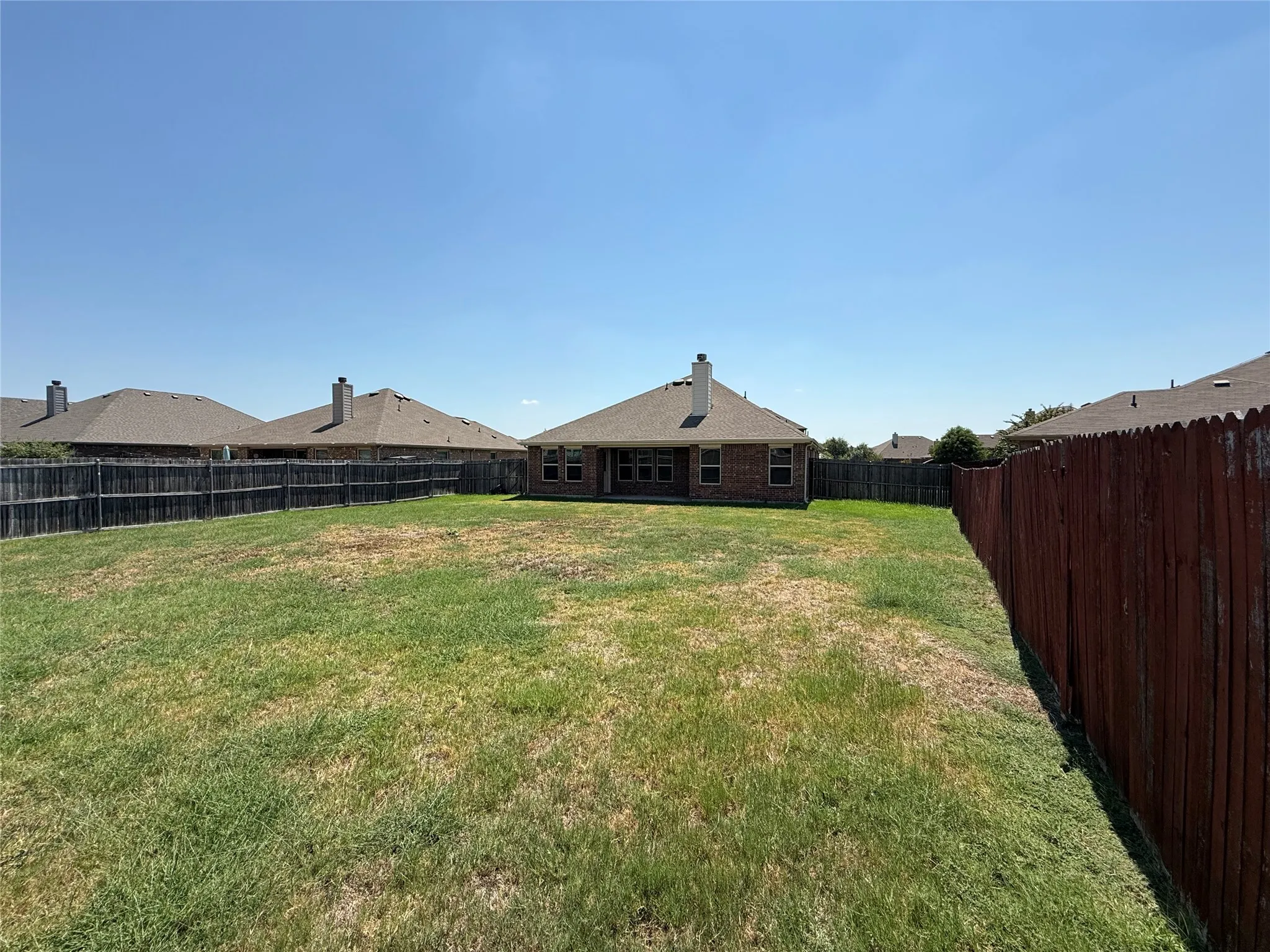 Expansive backyard with a wood privacy fence and a brick-faced exterior