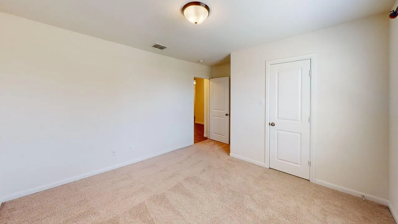 Neutral tone walls, carpeted flooring, and a flush mount ceiling light fixture