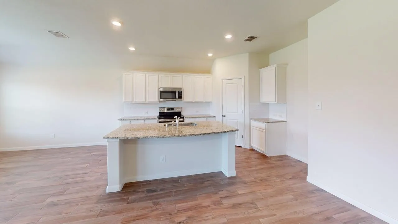 Kitchen featuring wood-finish flooring, white cabinetry, a large kitchen island with a sink, and stainless steel appliances