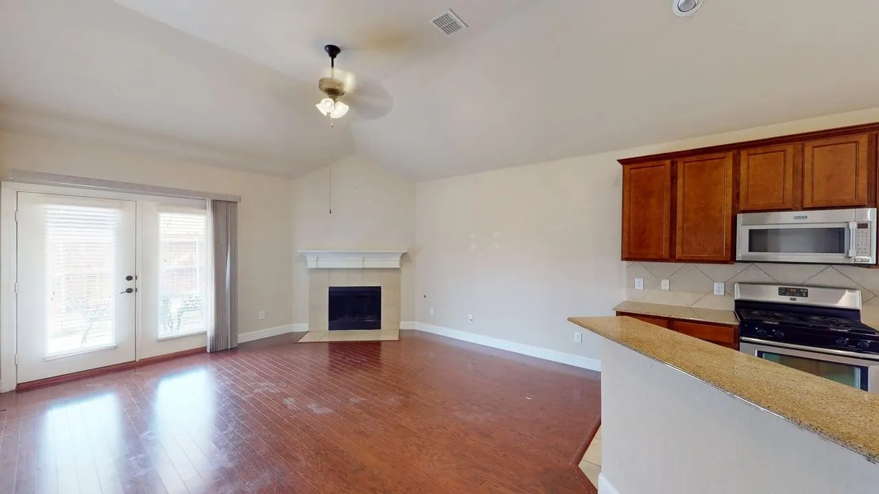 Wood-finish flooring, vaulted ceiling, built-in fireplace, stainless steel appliances, and wood cabinetry