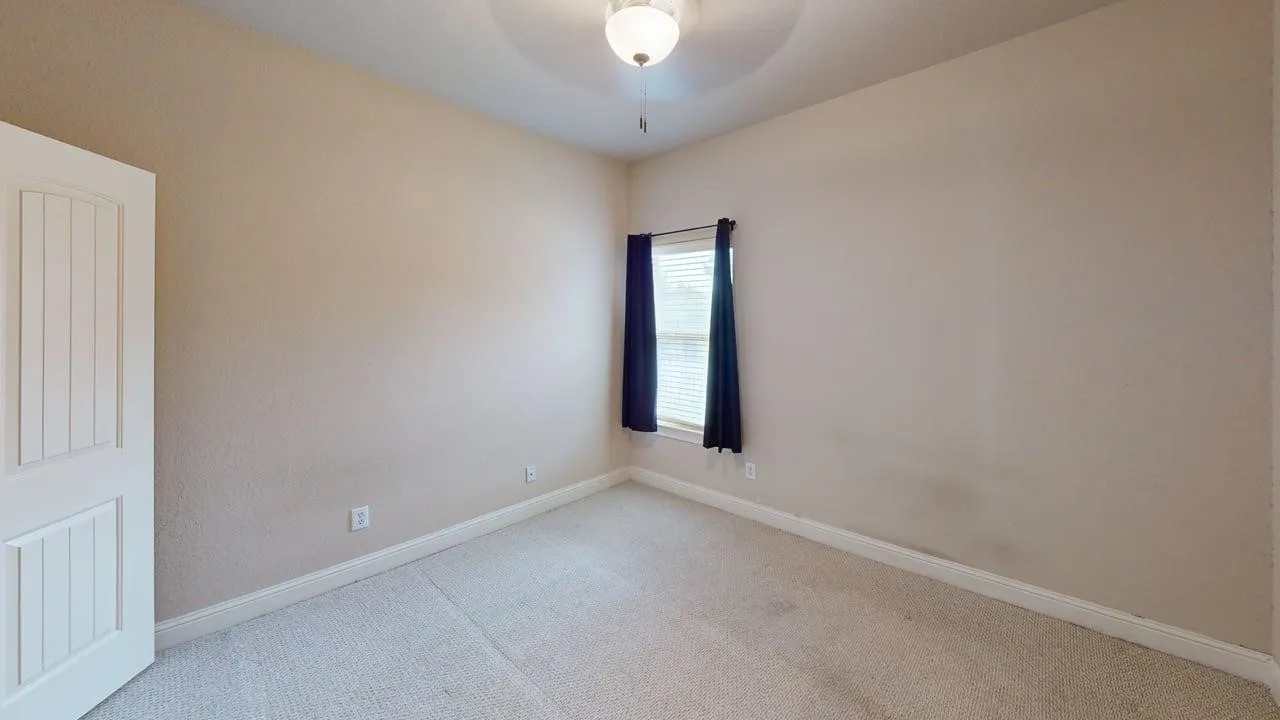 Textured neutral walls, carpeted flooring, and a single window with blinds