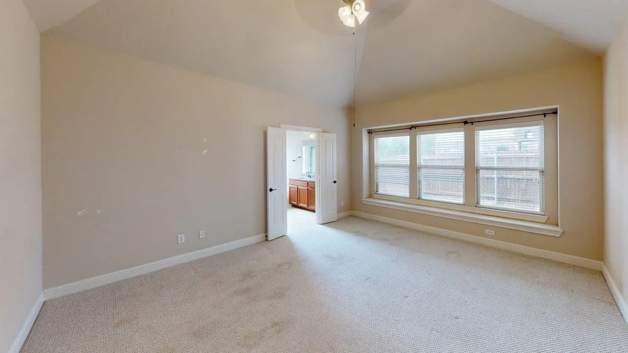 Vaulted ceiling with a ceiling fan, broad window with horizontal blinds, and a window seat