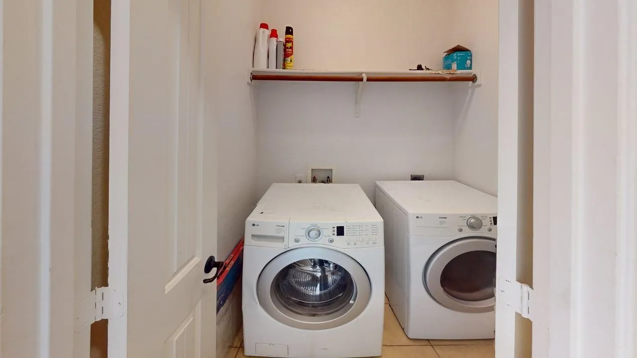 Dedicated laundry area with tile flooring and an overhead storage shelf
