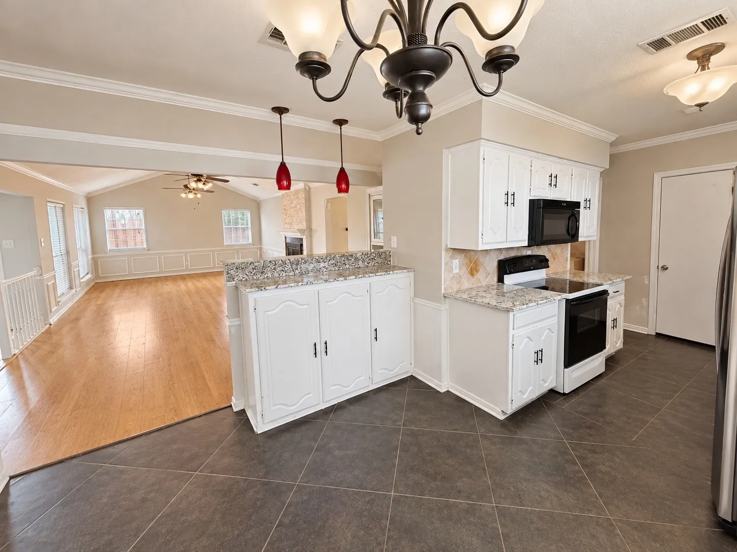 Kitchen with granite countertops, white cabinetry, tile flooring, and a built-in microwave