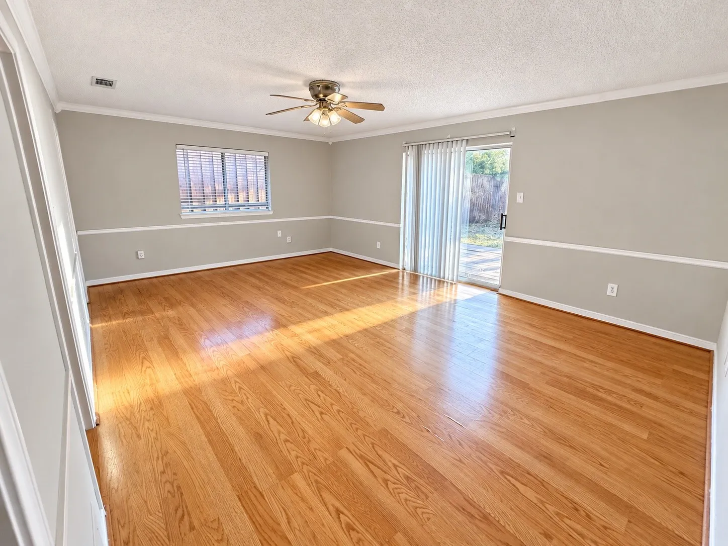 Hardwood flooring, crown molding, chair rail detailing, ceiling fan with integrated lighting, and sliding glass door