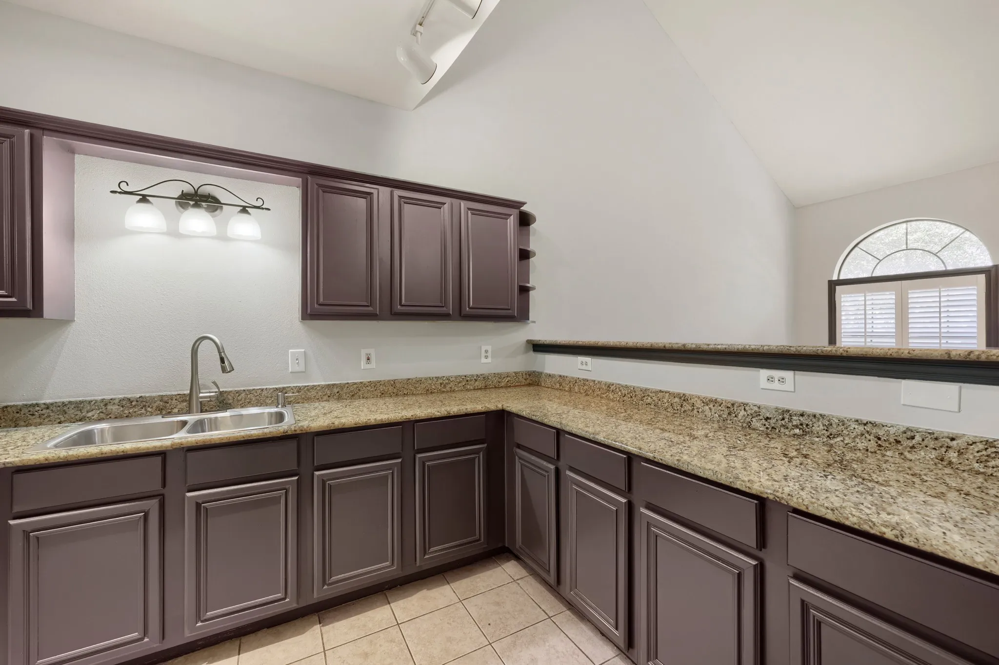 Kitchenette with brown cabinetry, light-toned countertops, and a dual basin stainless steel sink