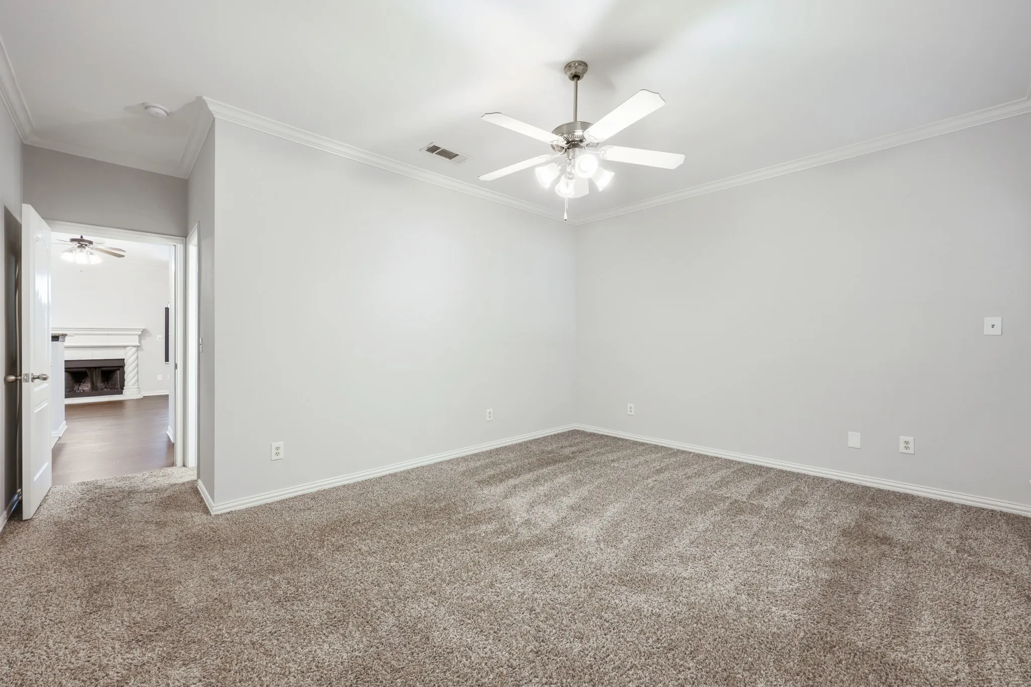 Plush carpeting, neutral wall tones, crown molding, and a ceiling fan with integrated lighting