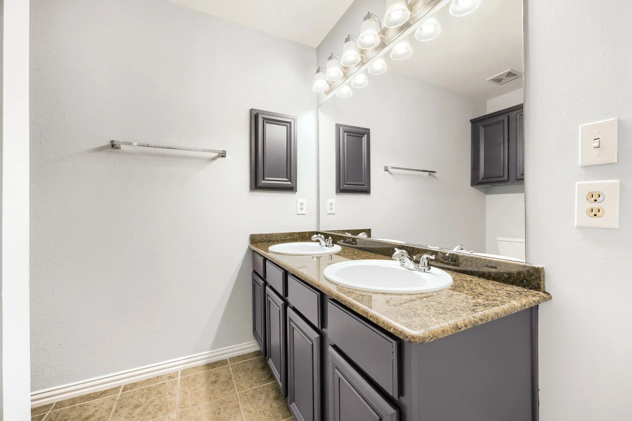 Dual vanity with undermount sinks, granite-finish countertop, and dark wood-finish cabinetry
