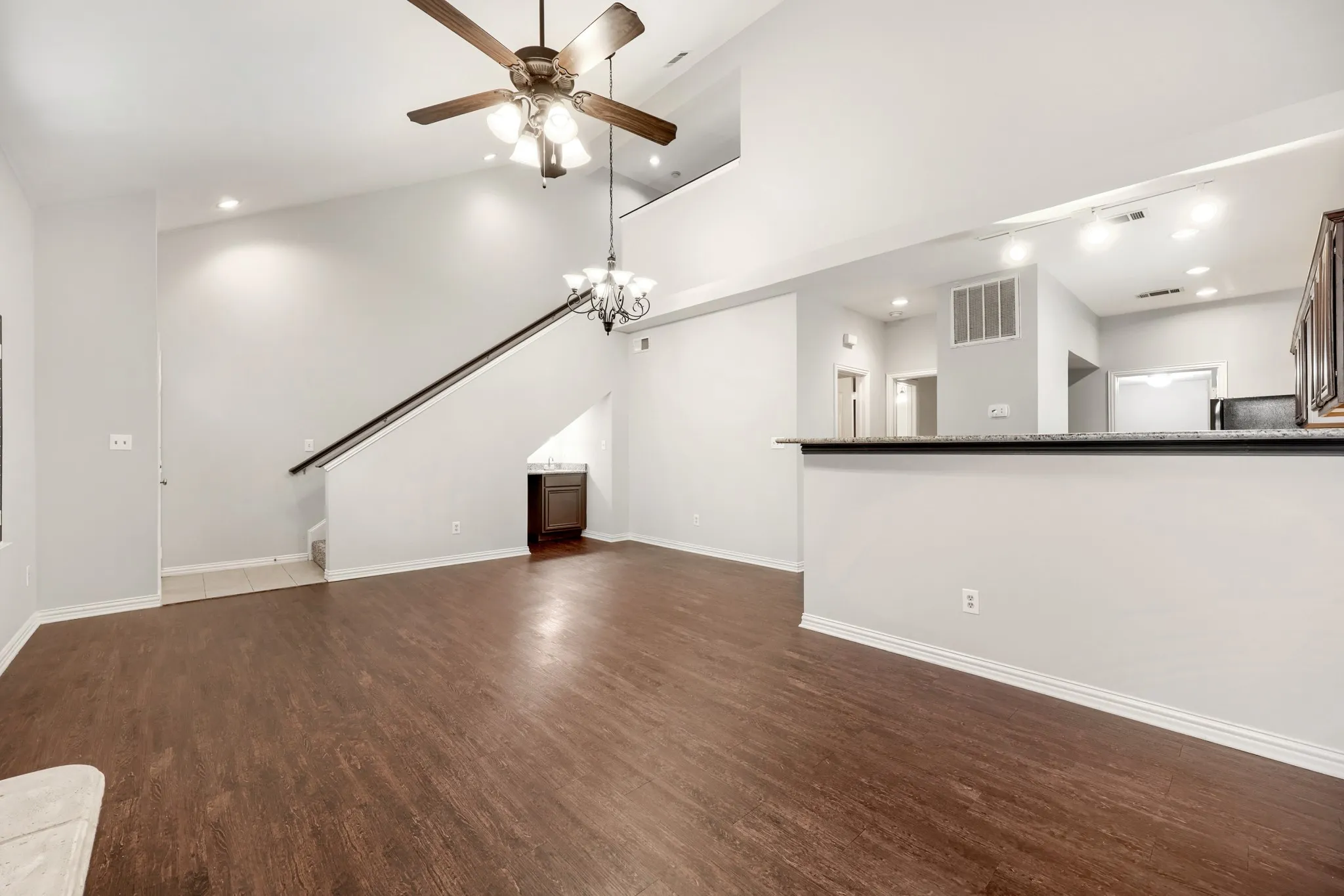 Vaulted ceiling with a ceiling fan, wood-finish flooring, recessed lighting, and an open-concept layout