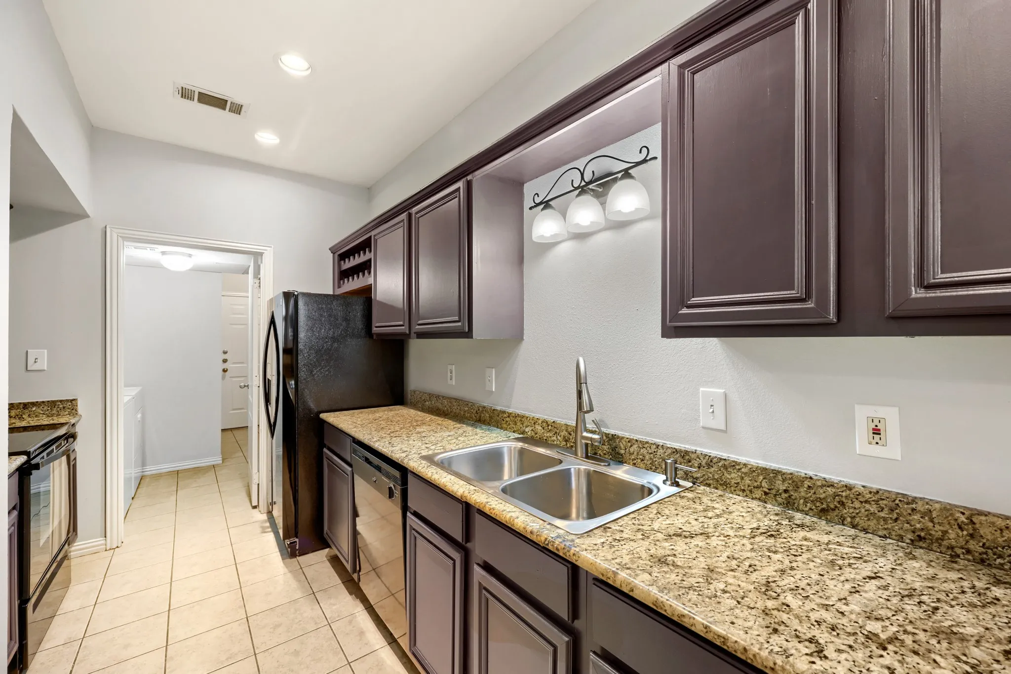 Kitchen featuring granite countertops, a double basin stainless steel sink, dark wood cabinetry, and recessed lighting