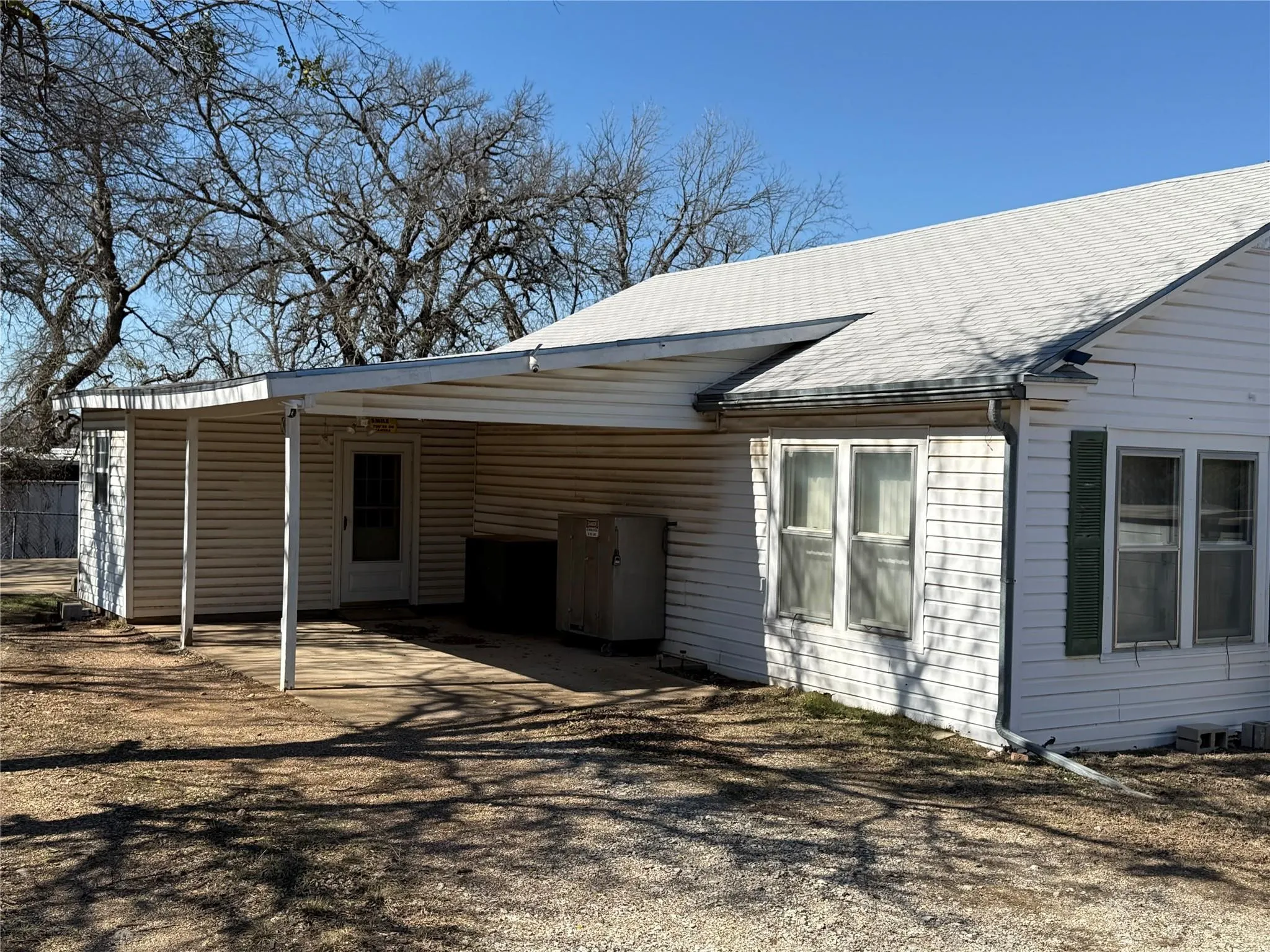 Rear exterior featuring white horizontal siding, a covered concrete patio, a light-colored asphalt shingle roof, and multiple windows