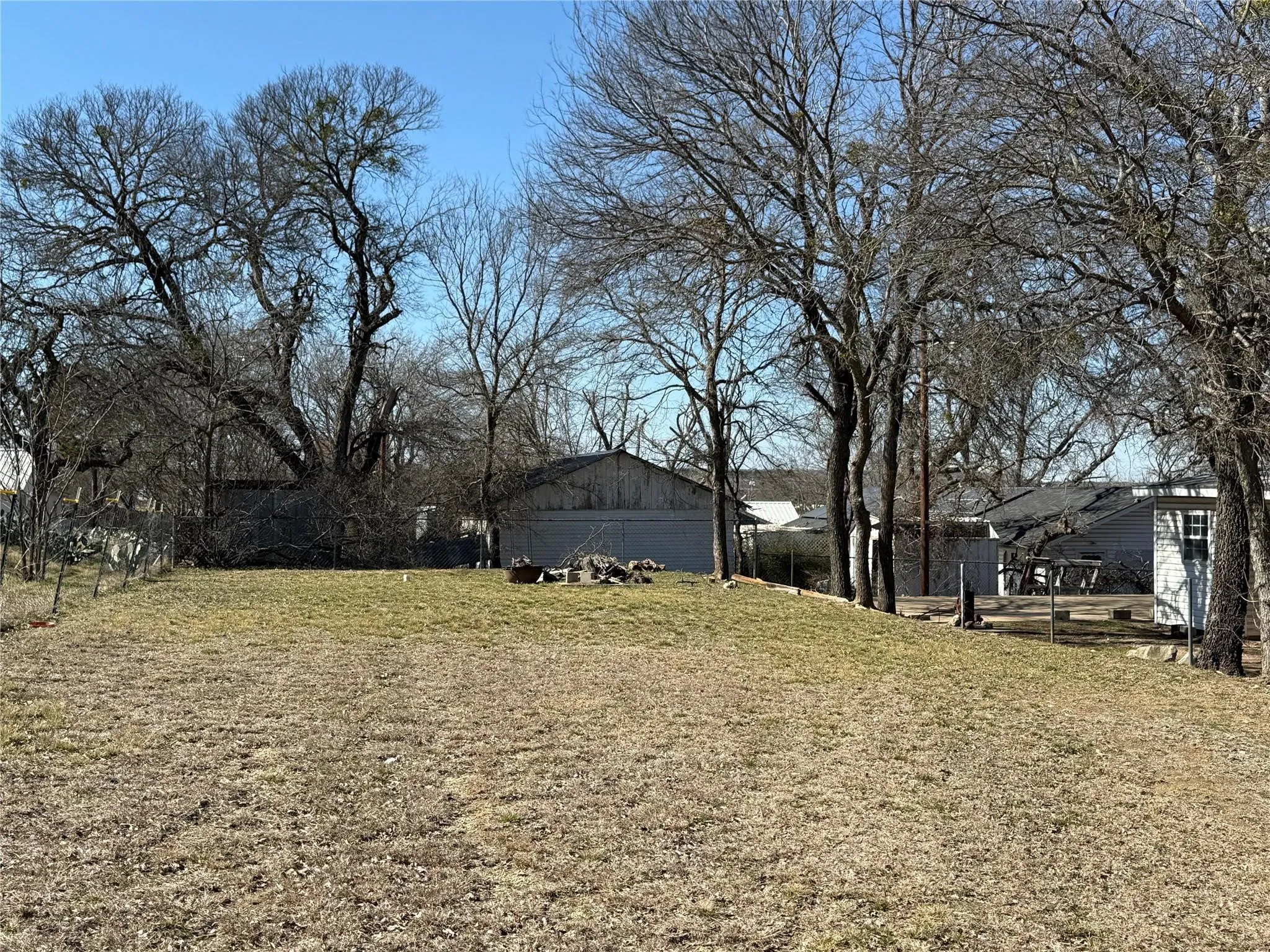 Expansive grassy terrain with mature trees and a clear sky