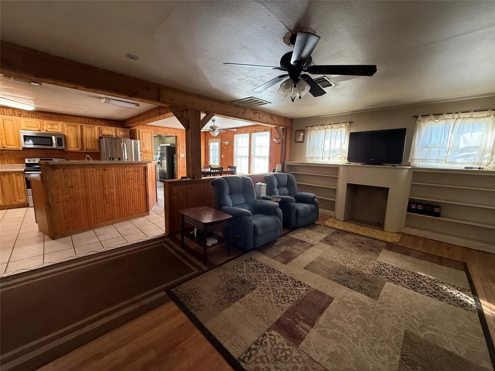 Open concept living area featuring a kitchen with wood-finish cabinetry, a built-in breakfast bar, and stainless steel appliances