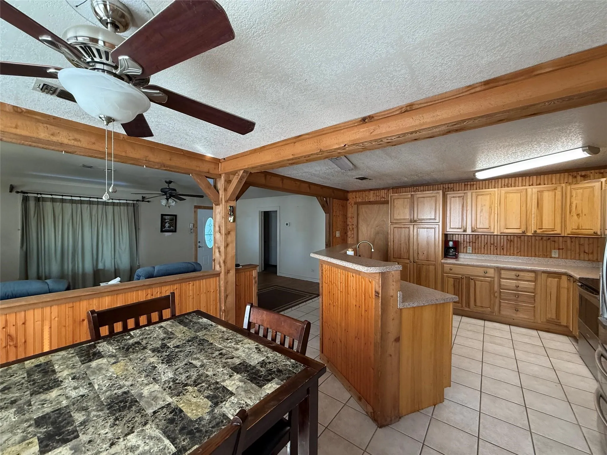 Kitchen featuring wood-finish cabinetry, tile flooring, and a breakfast bar with a solid surface countertop