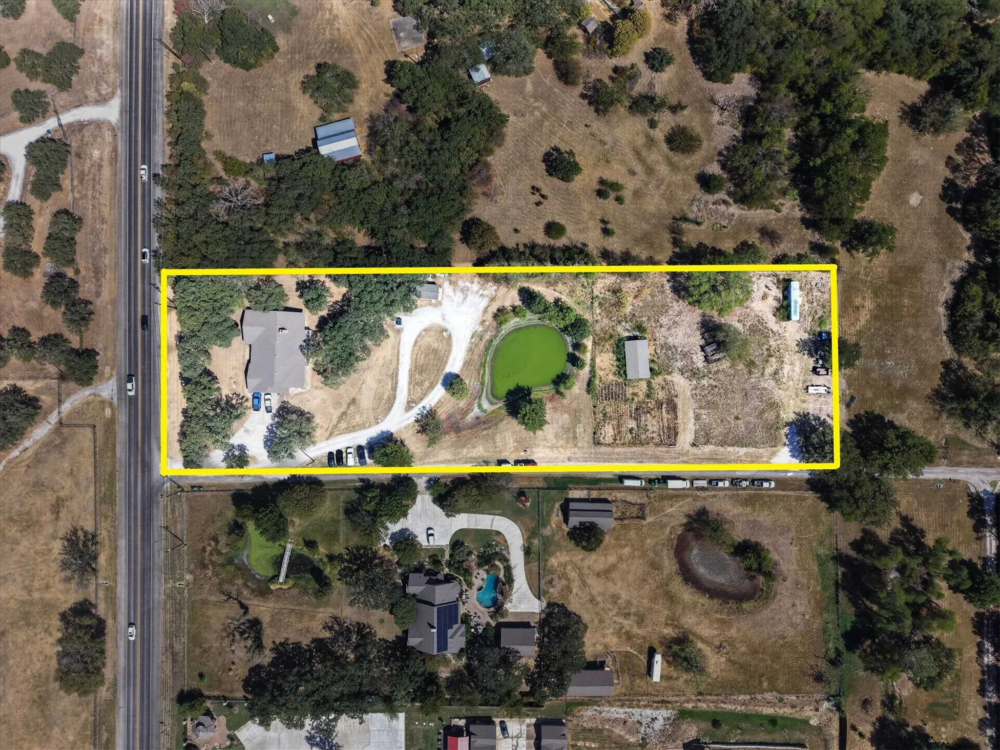 Overhead perspective with approximate property boundaries outlined, highlighting the pond, existing improvements, and road frontage.