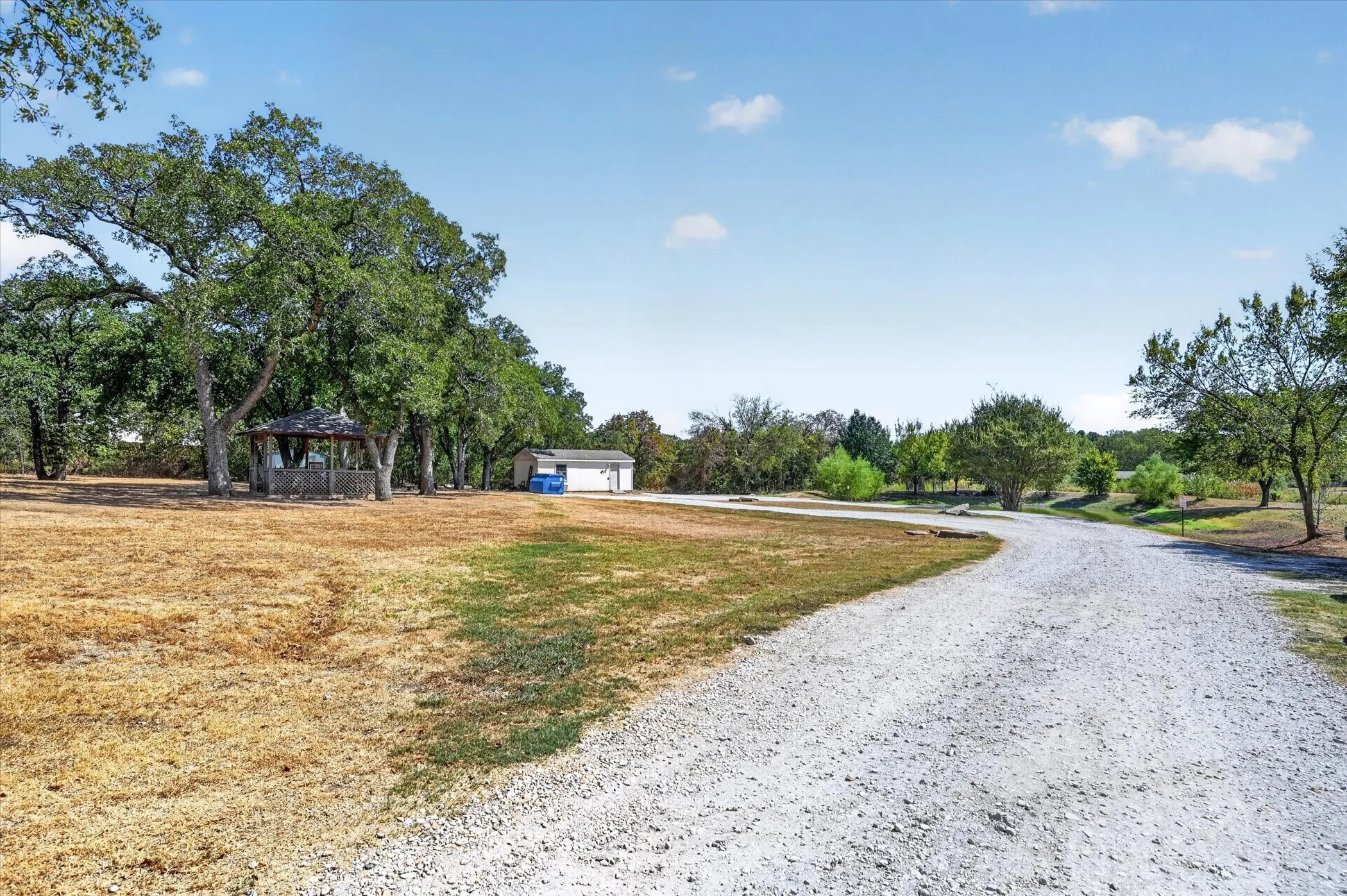 Interior property drive surrounded by open space and mature trees.