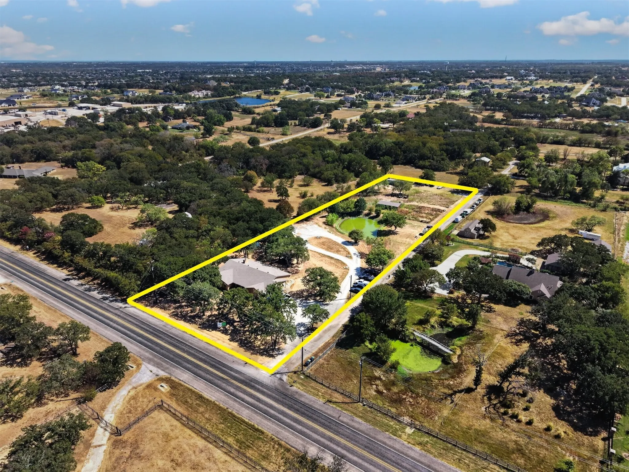 Property boundaries outlined, showcasing the expansive acreage, FM 407 frontage, existing residence, pond, and mature trees.