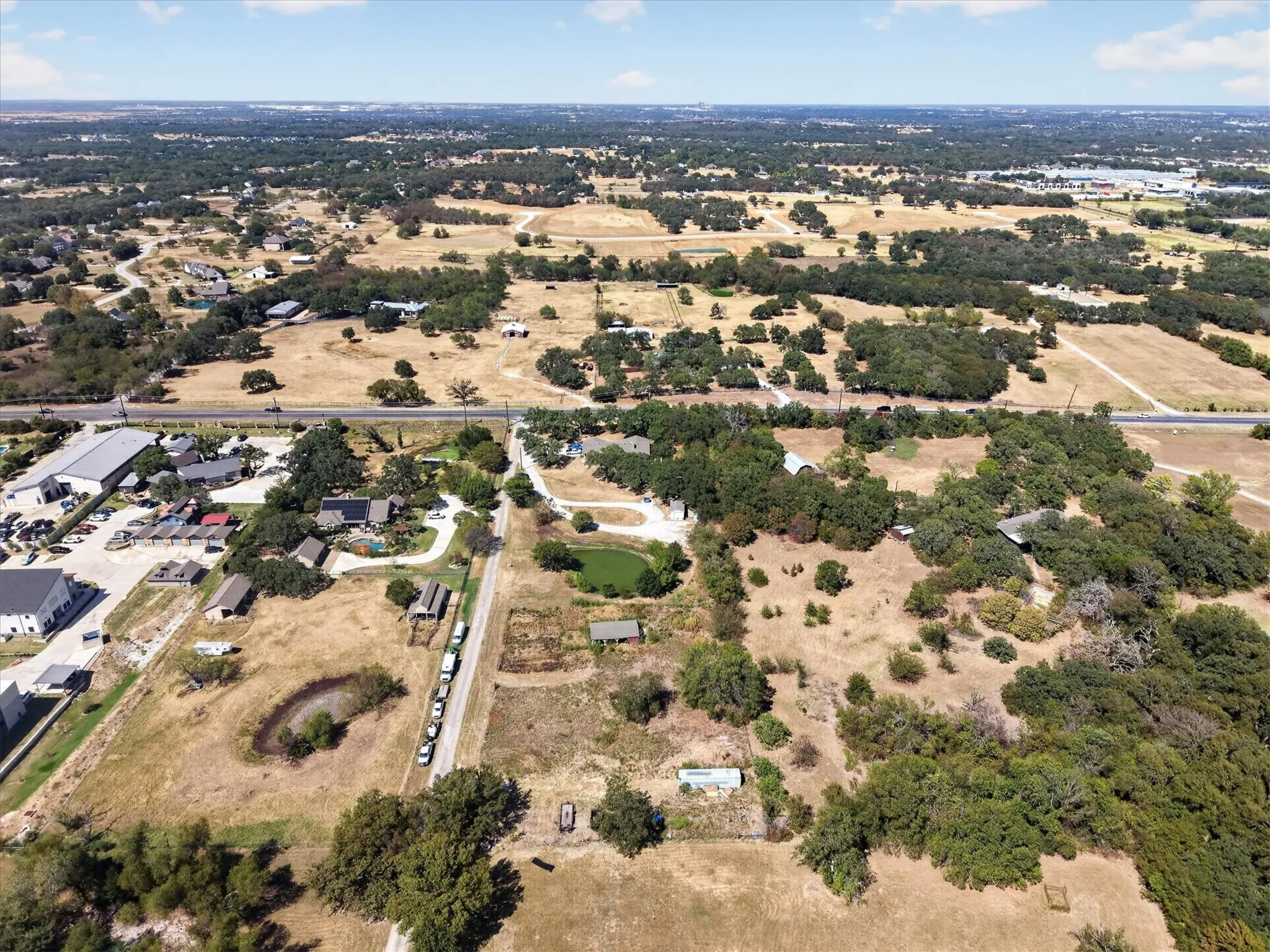 Top-down aerial view showcasing the property layout, pond, driveway, and improvements.