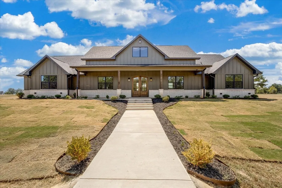 Modern farmhouse exterior featuring board and batten siding, a covered entry porch with wood columns, and a prominent gable roofline