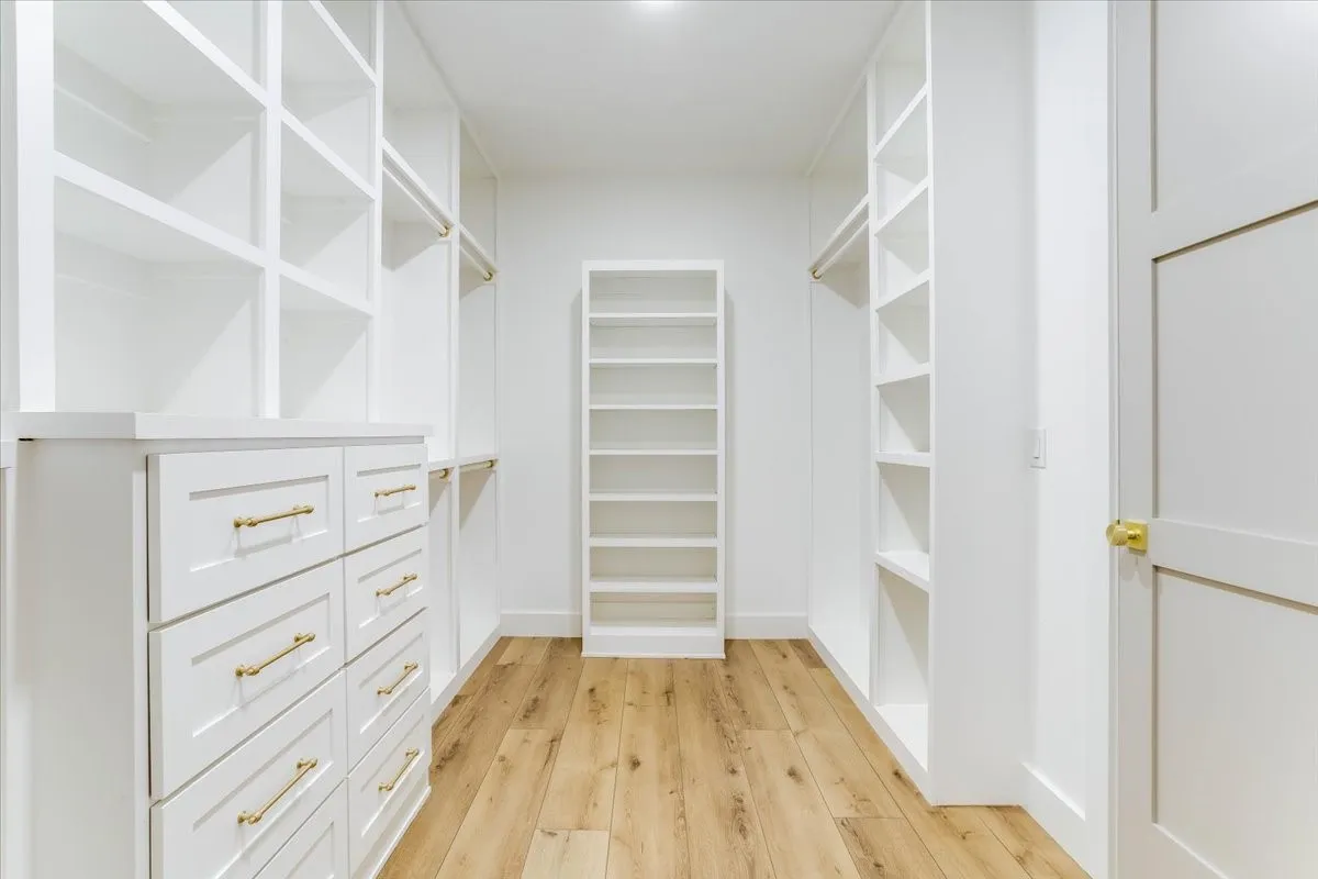 Custom closet system featuring built-in shelving, drawers with gold-toned hardware, and a center storage unit
