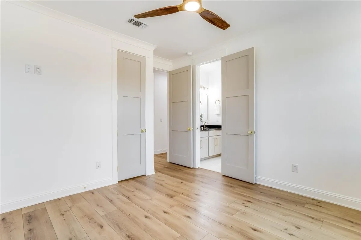 Wood-finish flooring, white walls, and crown molding