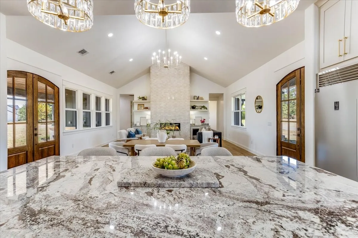 Spacious open-concept interior featuring vaulted ceilings, wood-finish flooring, and a stone fireplace