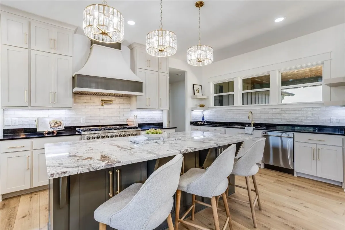 Gourmet kitchen with a large island, stainless steel appliances, pristine white subway tile backsplash, and light wood-finish flooring