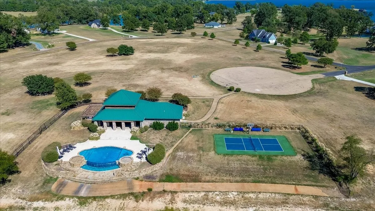Property features a turquoise-roofed structure, an irregularly shaped swimming pool, a stone-lined hot tub, and an outdoor court