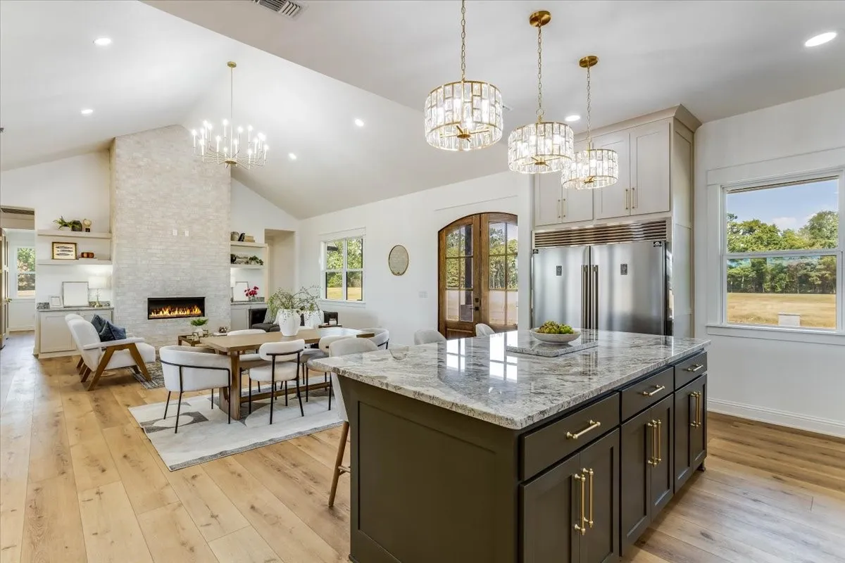 Spacious living area featuring vaulted ceilings, a fireplace with a stone surround, and wood-finish flooring