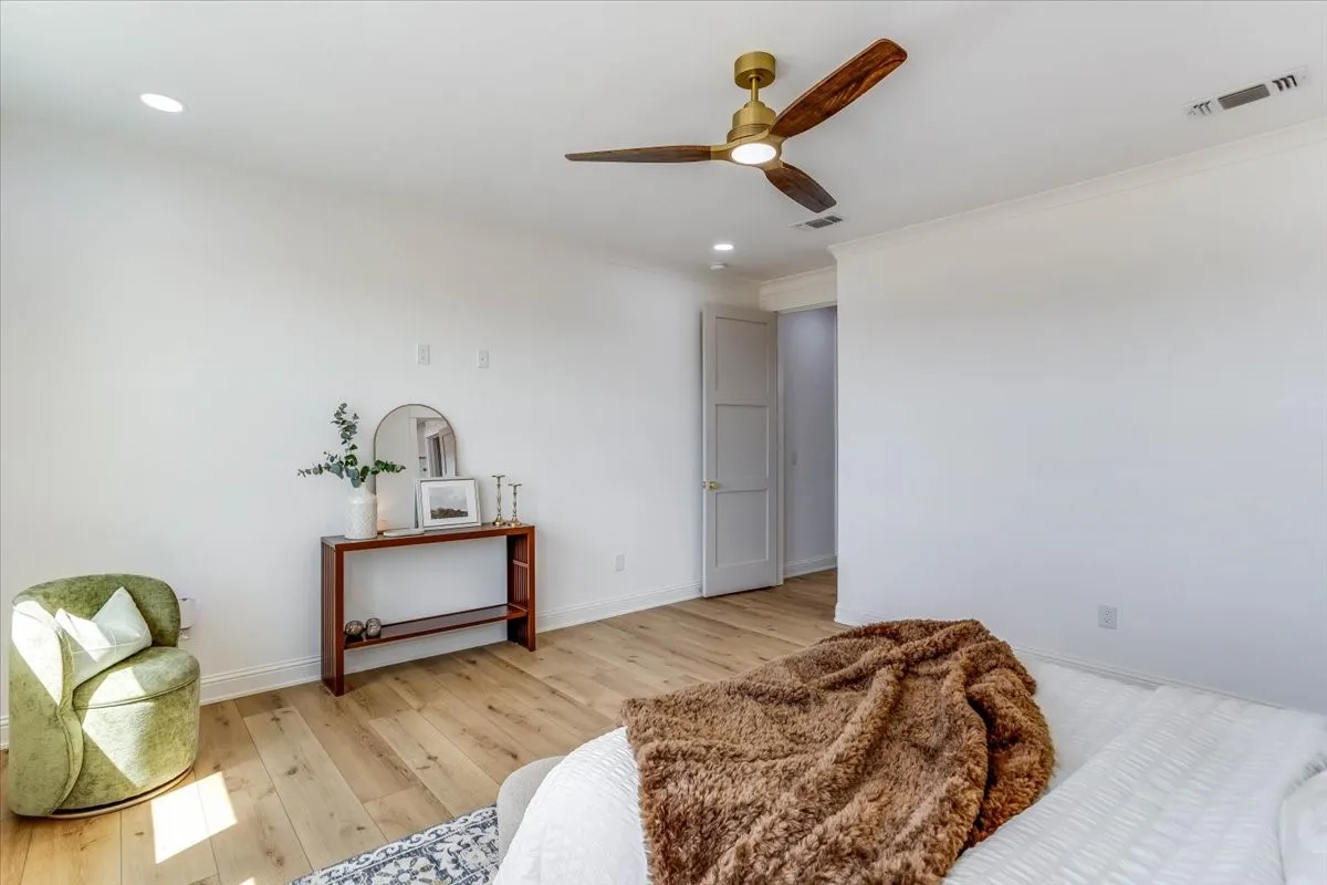 Wood-finish flooring, recessed lighting, crown molding, ceiling fan with light fixture, and a paneled door