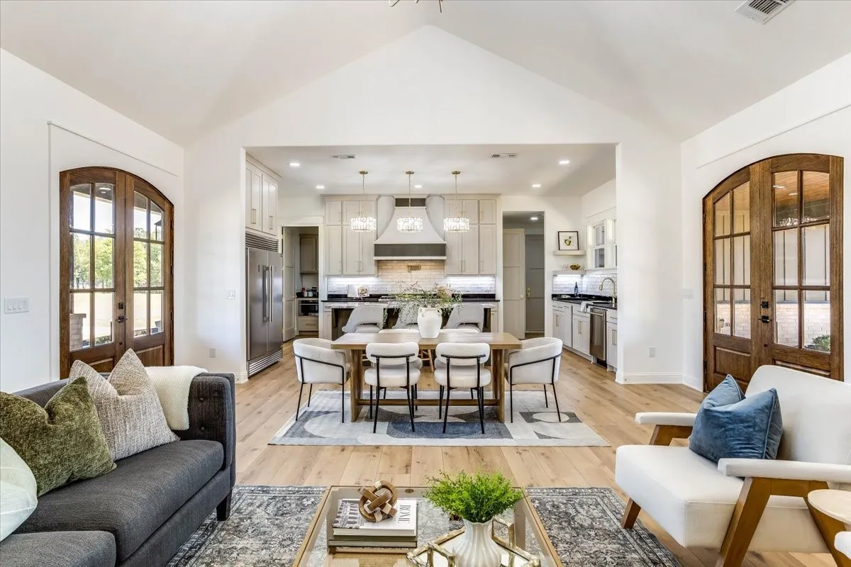 Vaulted ceilings, wood-finish flooring, arched paneled glass doors, stainless steel appliances, and integrated kitchen cabinetry