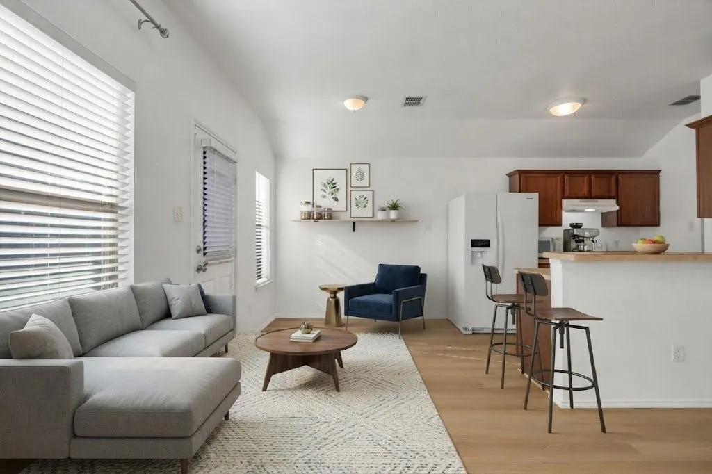 Open-concept living space featuring wood-finish flooring, vaulted ceilings, and a kitchen with wood cabinetry