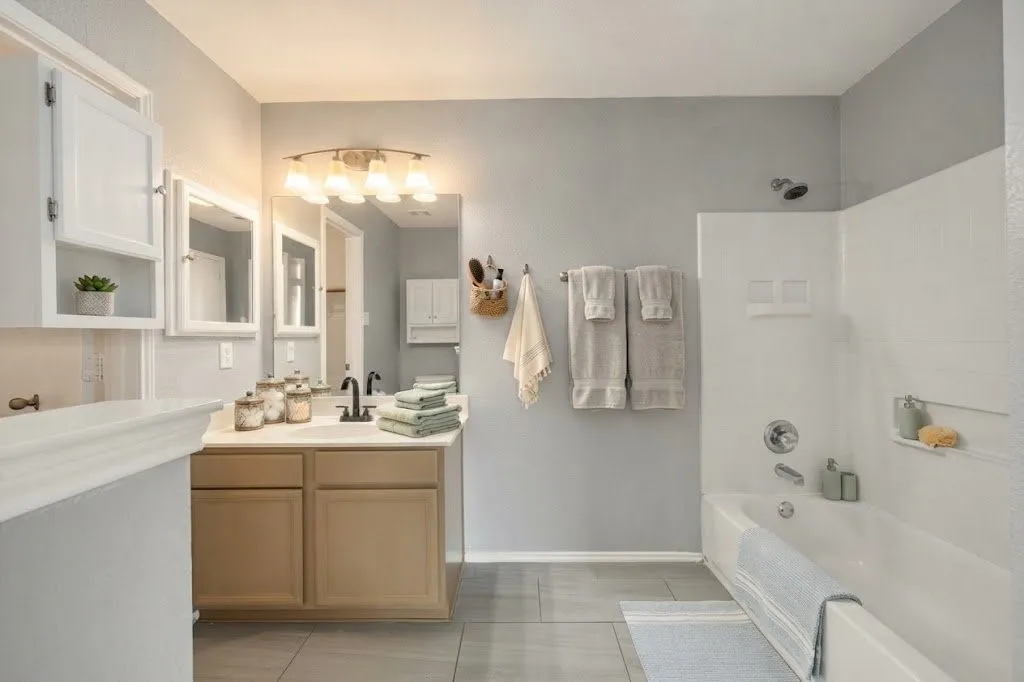 Dual vanity with individual framed mirrors, light wood-finish cabinetry, and matte black plumbing fixtures
