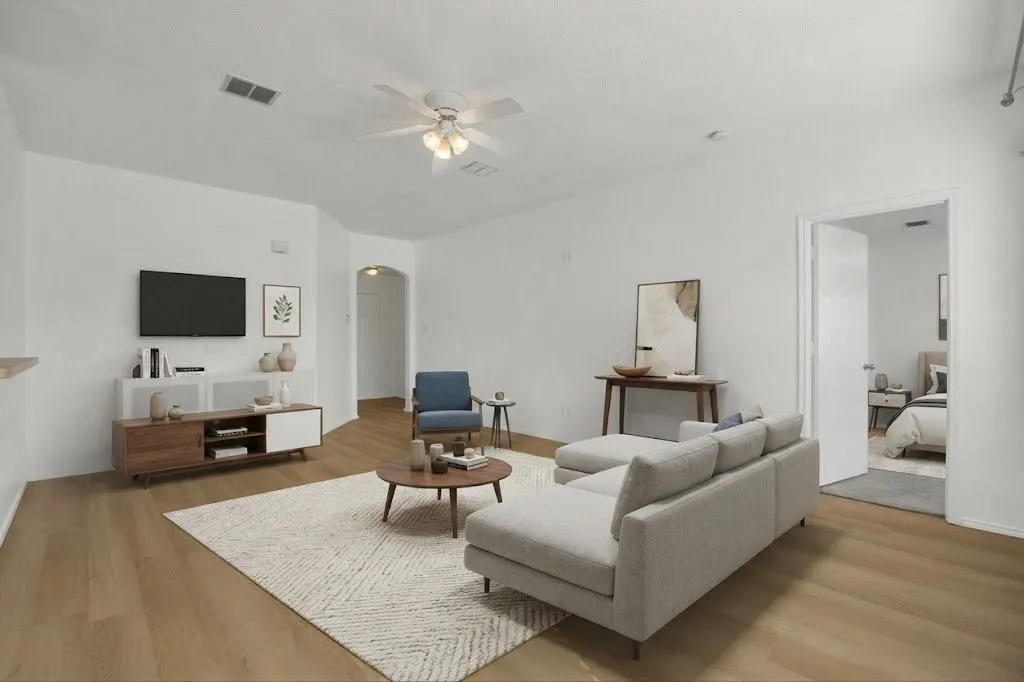 Wood-finish flooring throughout, white painted walls, and a ceiling fan with integrated lighting