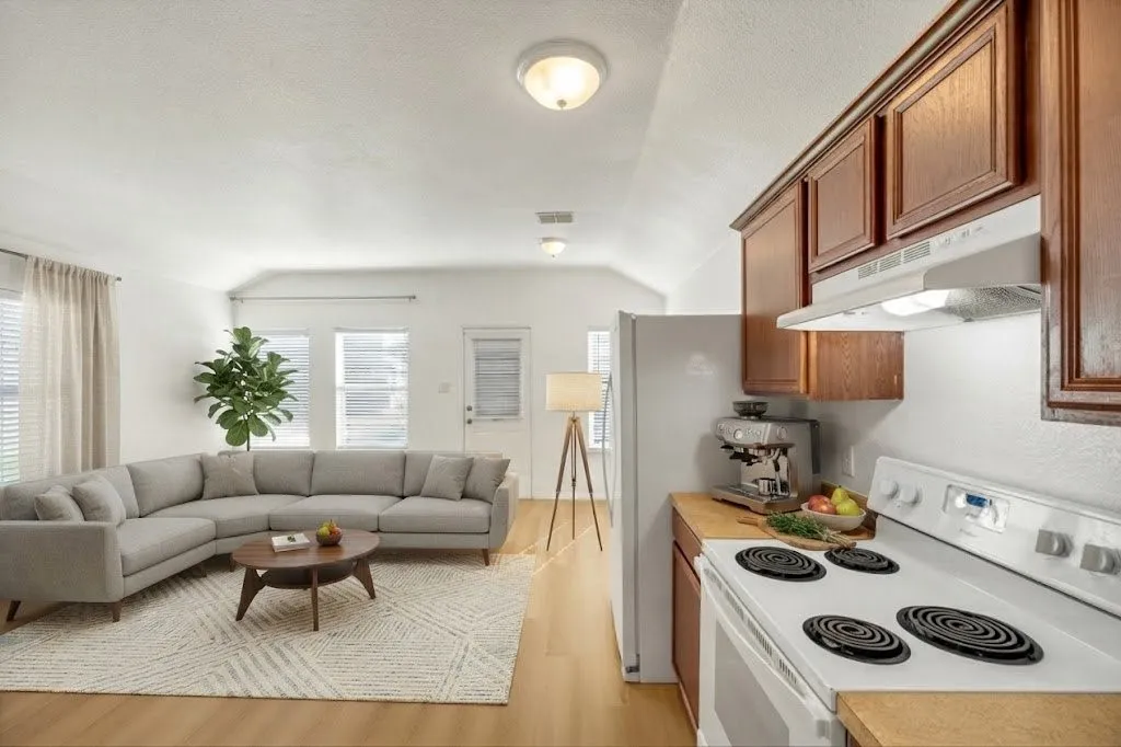Vaulted ceiling, recessed lighting, wood-finish flooring, wood cabinetry, and a range with overhead ventilation