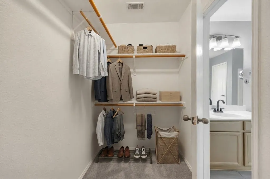Built-in closet shelving, double hanging rods, and gray carpeting