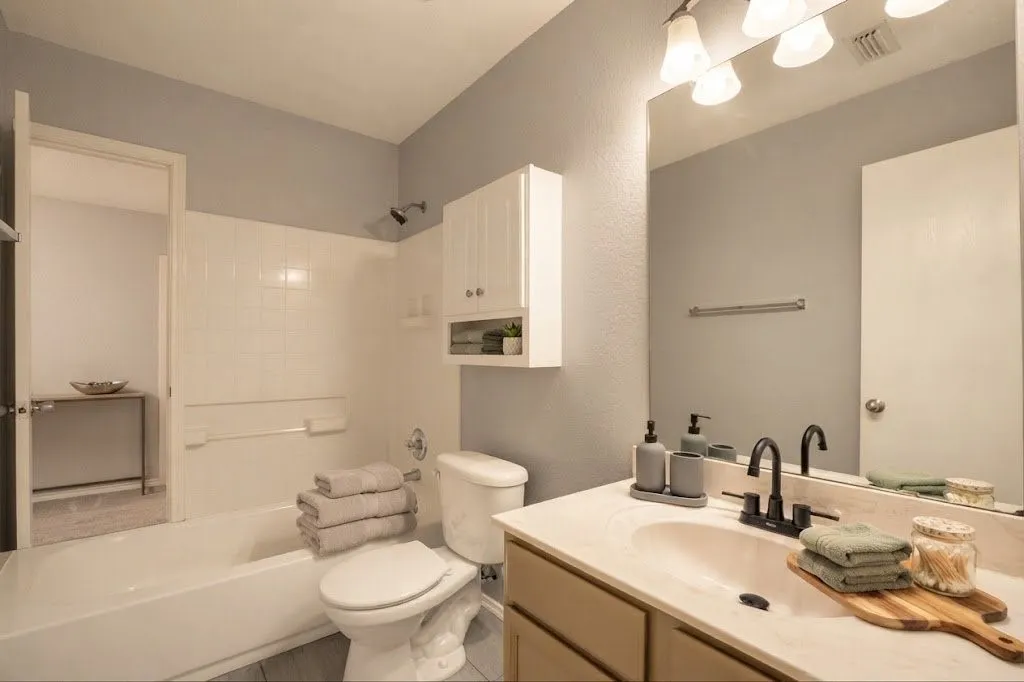 Bathroom featuring a single vanity with an integrated sink, matte black faucet, and a wall-mounted mirror