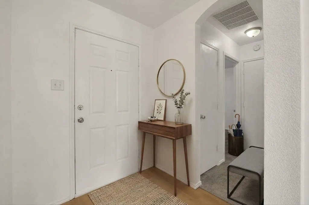 Light wood-finish flooring with a white paneled door and archway