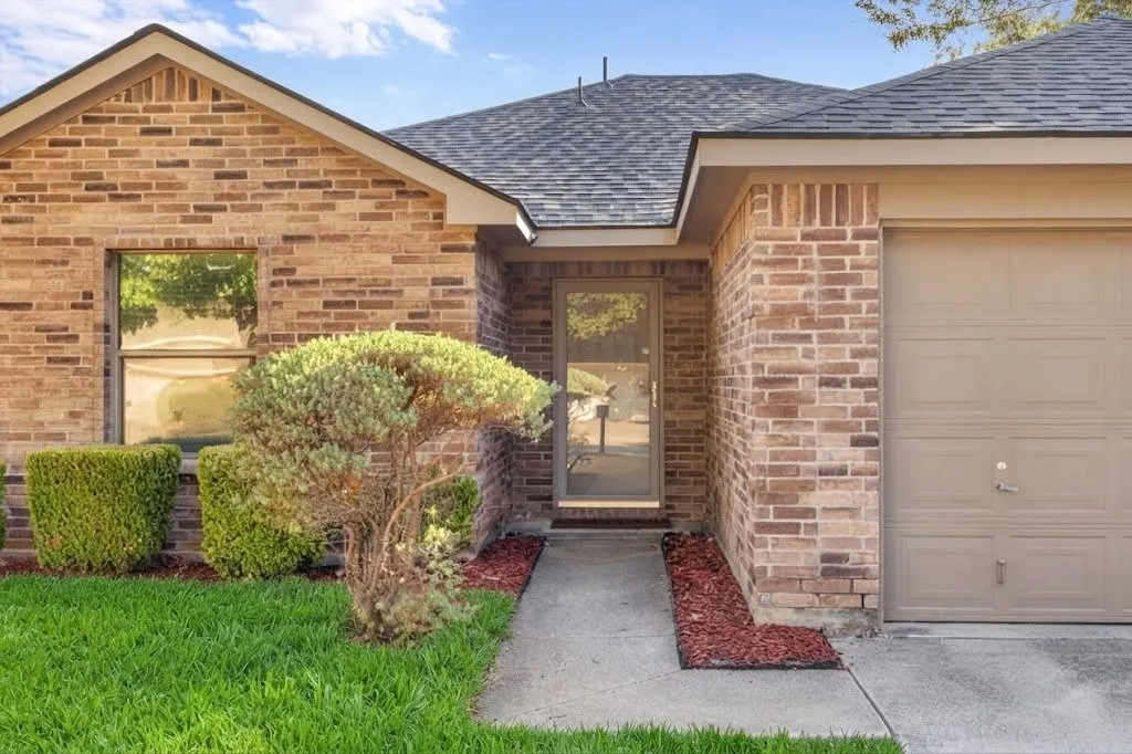 Brick exterior with a gabled roofline, concrete walkway, and an attached garage