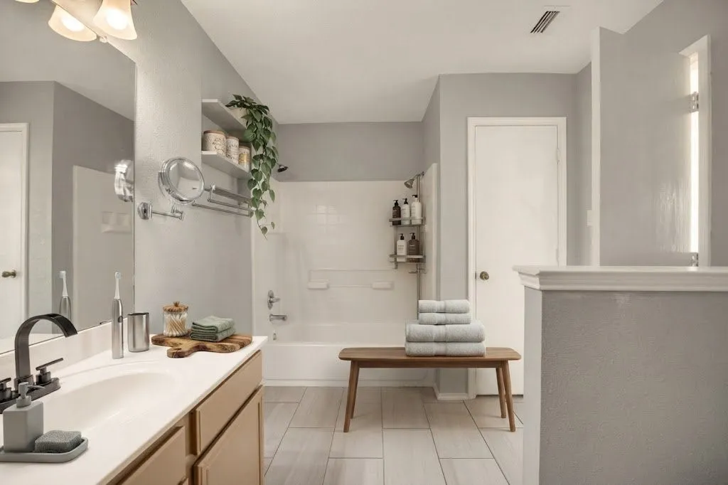 Bathroom featuring a single vanity with a white countertop and matte black faucet, a bathtub with a shower, and tile flooring
