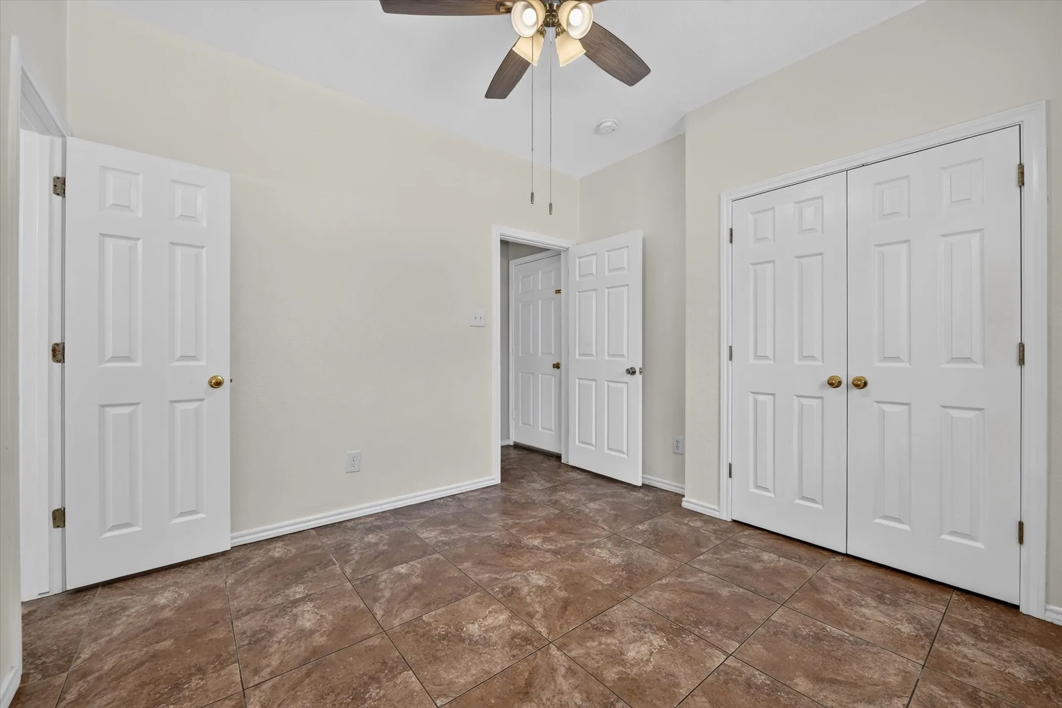 Textured tile flooring, paneled interior doors, and a ceiling fan with integrated lighting