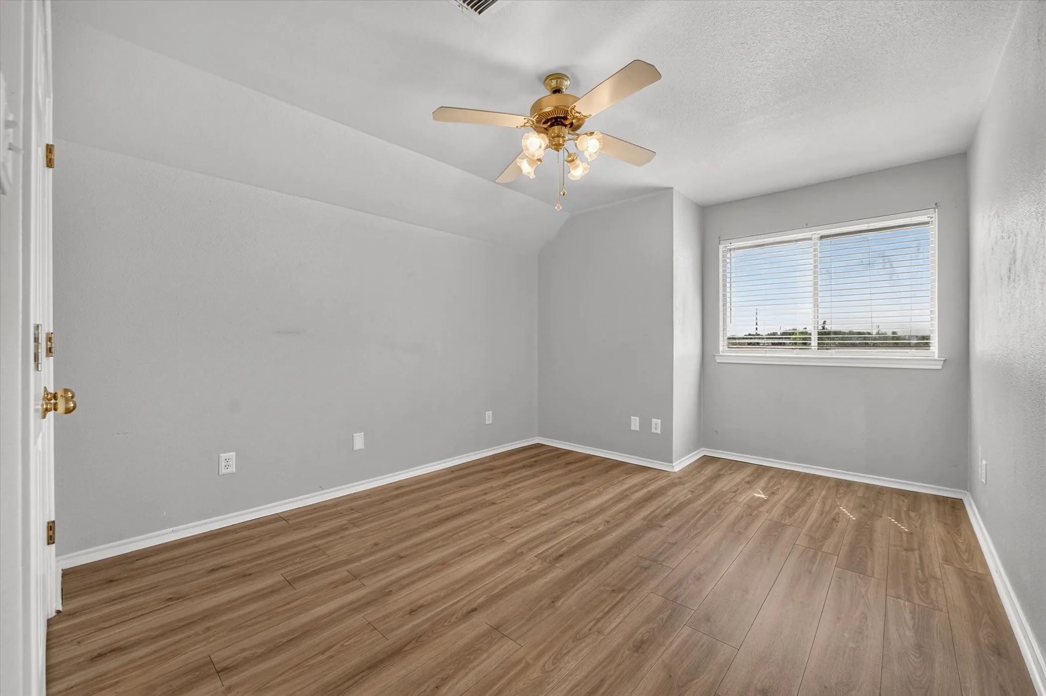 Wood-finish flooring, ceiling fan with integrated lighting, window with blinds, and white trim