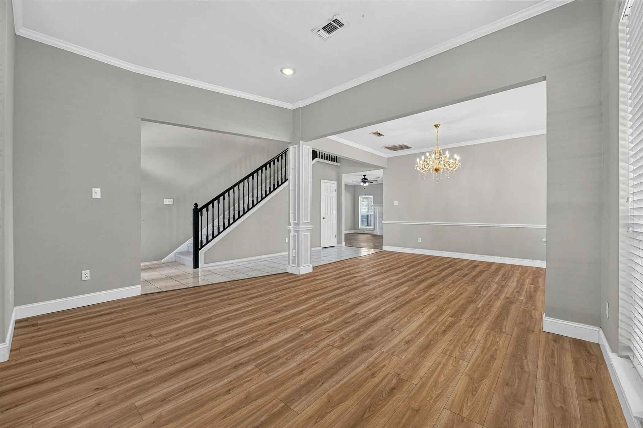 Expansive room featuring wood-finish flooring, crown molding, and a decorative chandelier