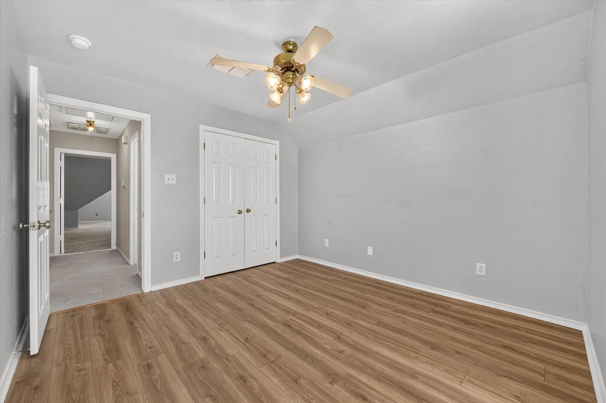 Wood-finish flooring, ceiling fan with integrated lighting, painted walls, and a bi-fold closet door