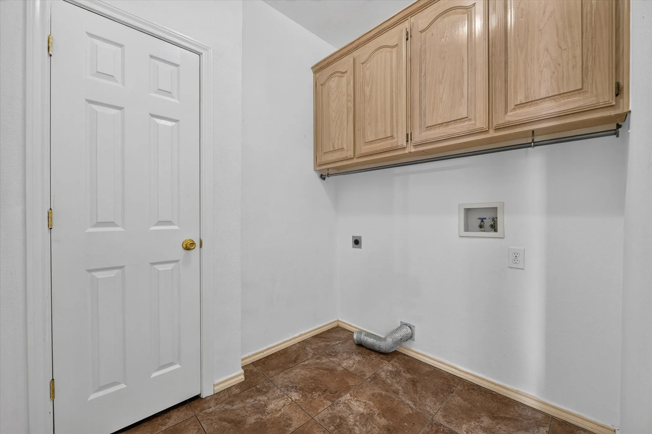 Light wood-finish cabinetry, tile flooring, and a six-panel interior door