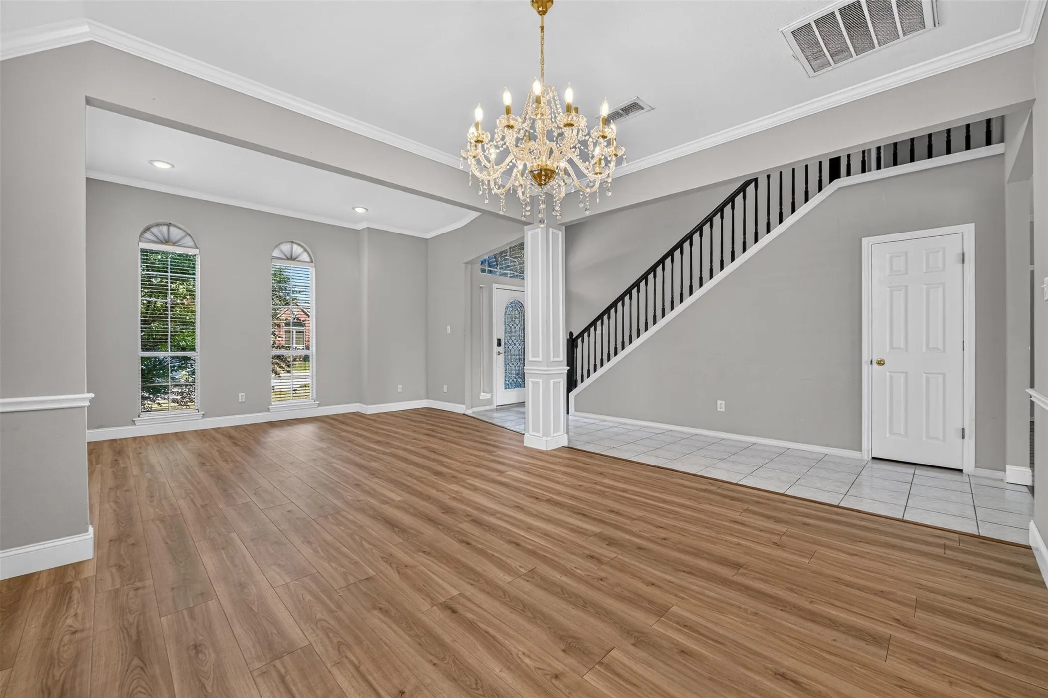Wood-finish flooring, recessed lighting, and a crystal chandelier complement the arched windows