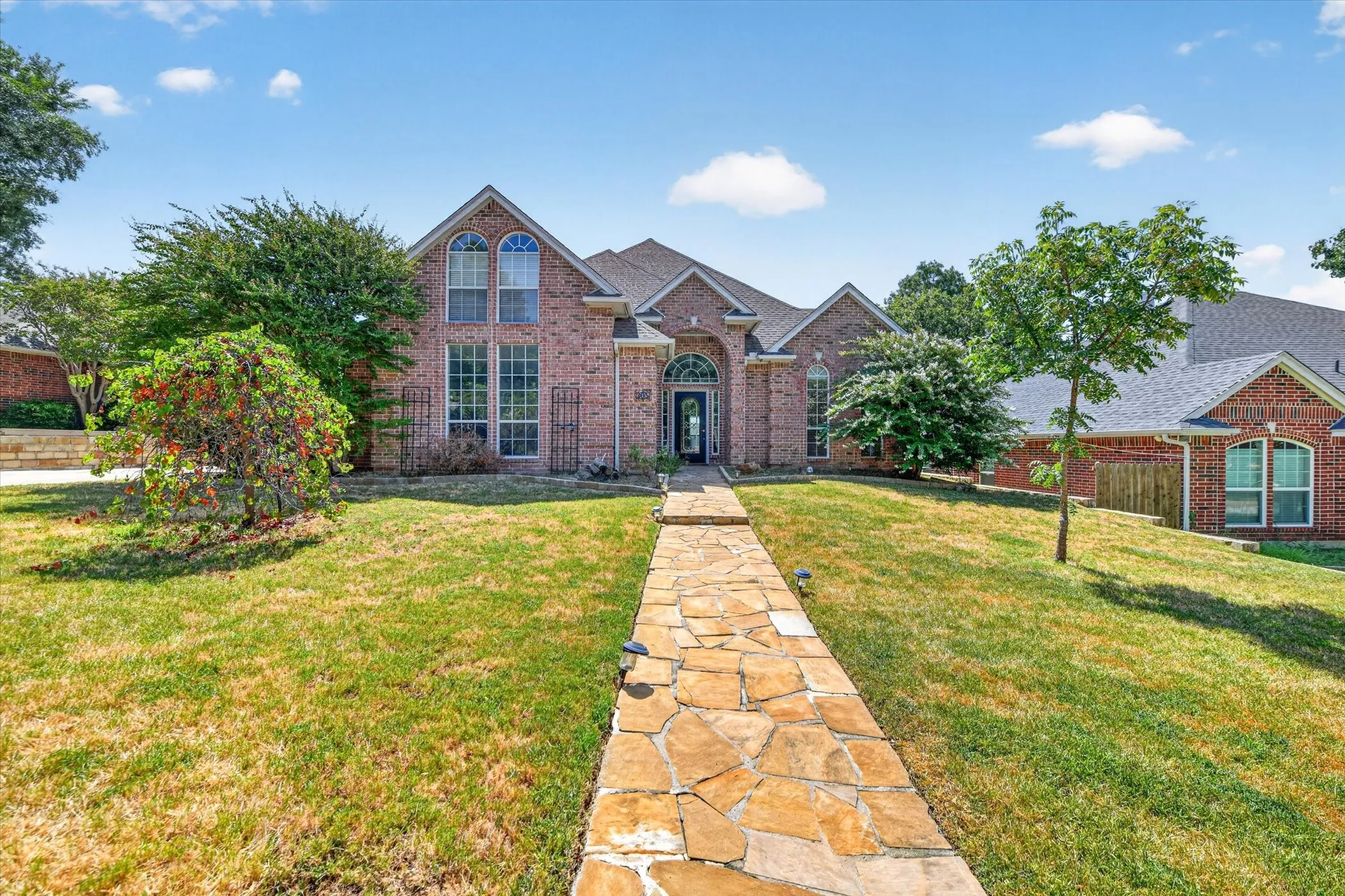 Traditional brick exterior with arched entry, multi-pane windows, and a stone-paver walkway