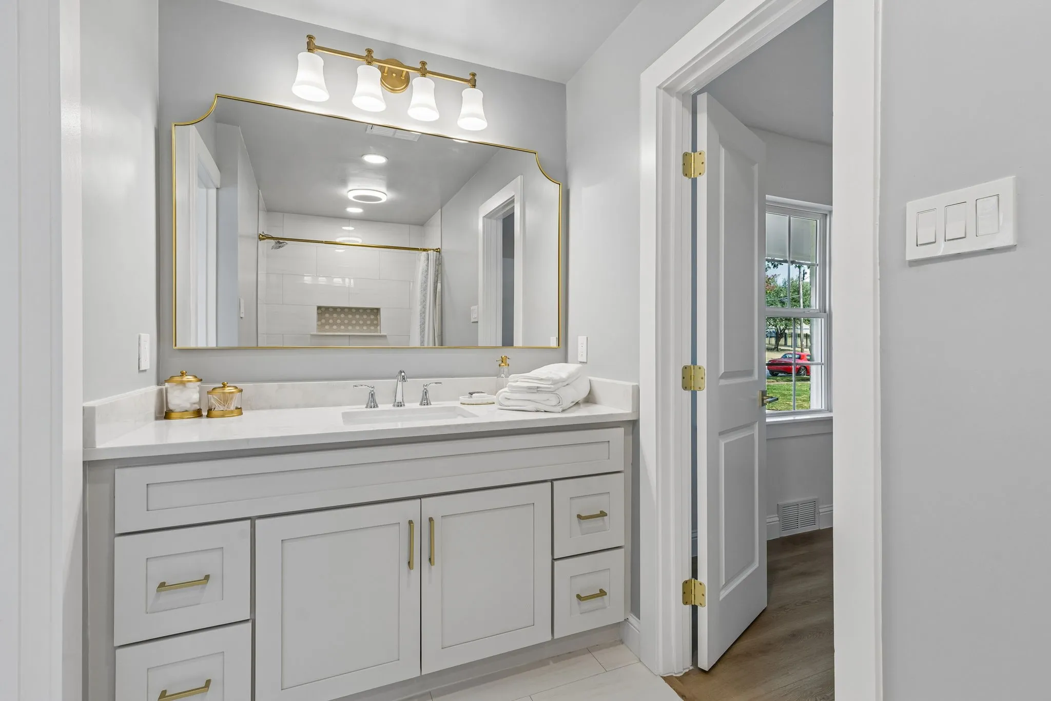 Jack and Jill bathroom with a shower/tub combo, glossy tile surround, decorative niche, and brushed gold fixtures for a polished touch.