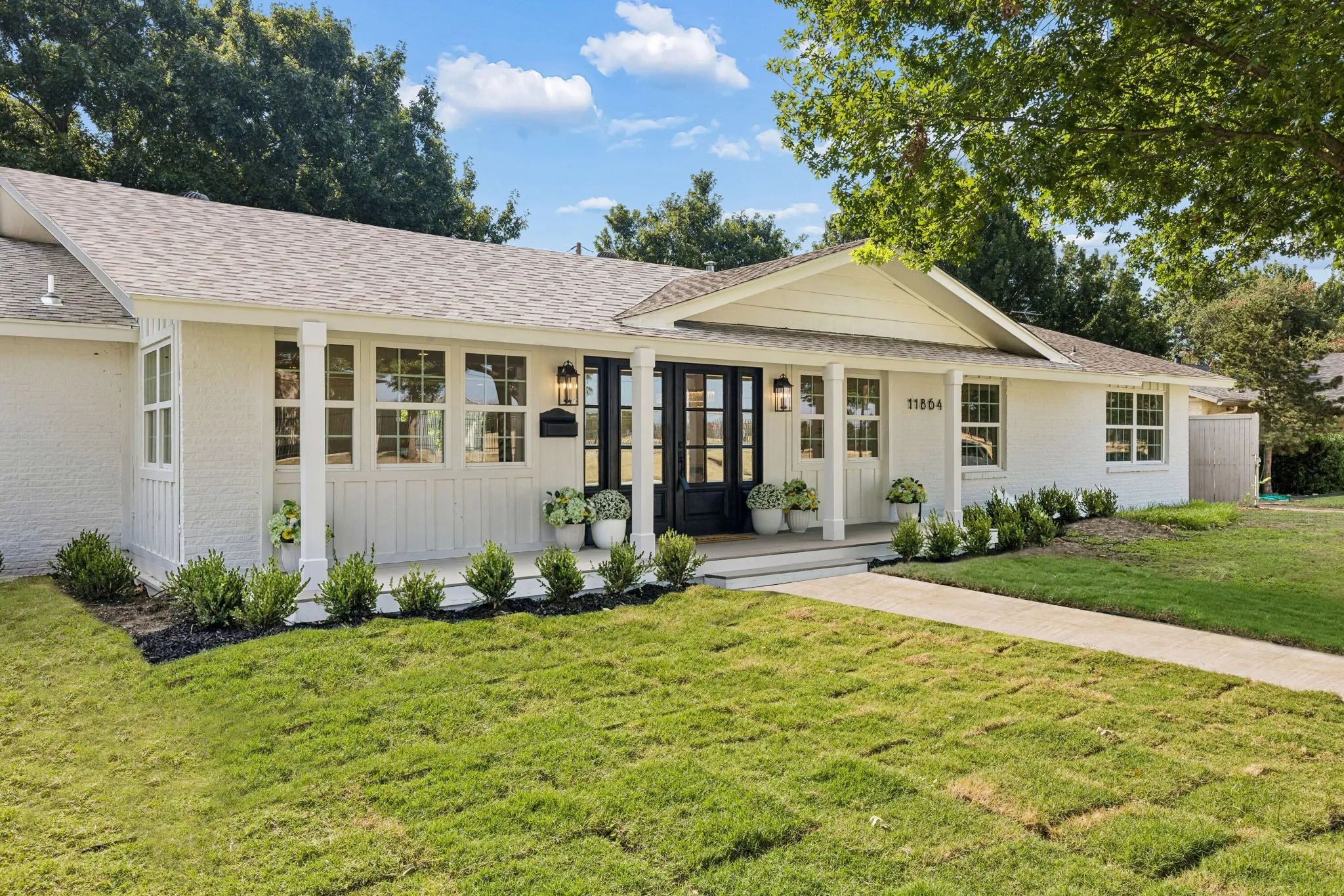Beautifully updated single-story home with a welcoming covered front porch, striking double front doors, mature trees and thoughtfully designed landscaping.