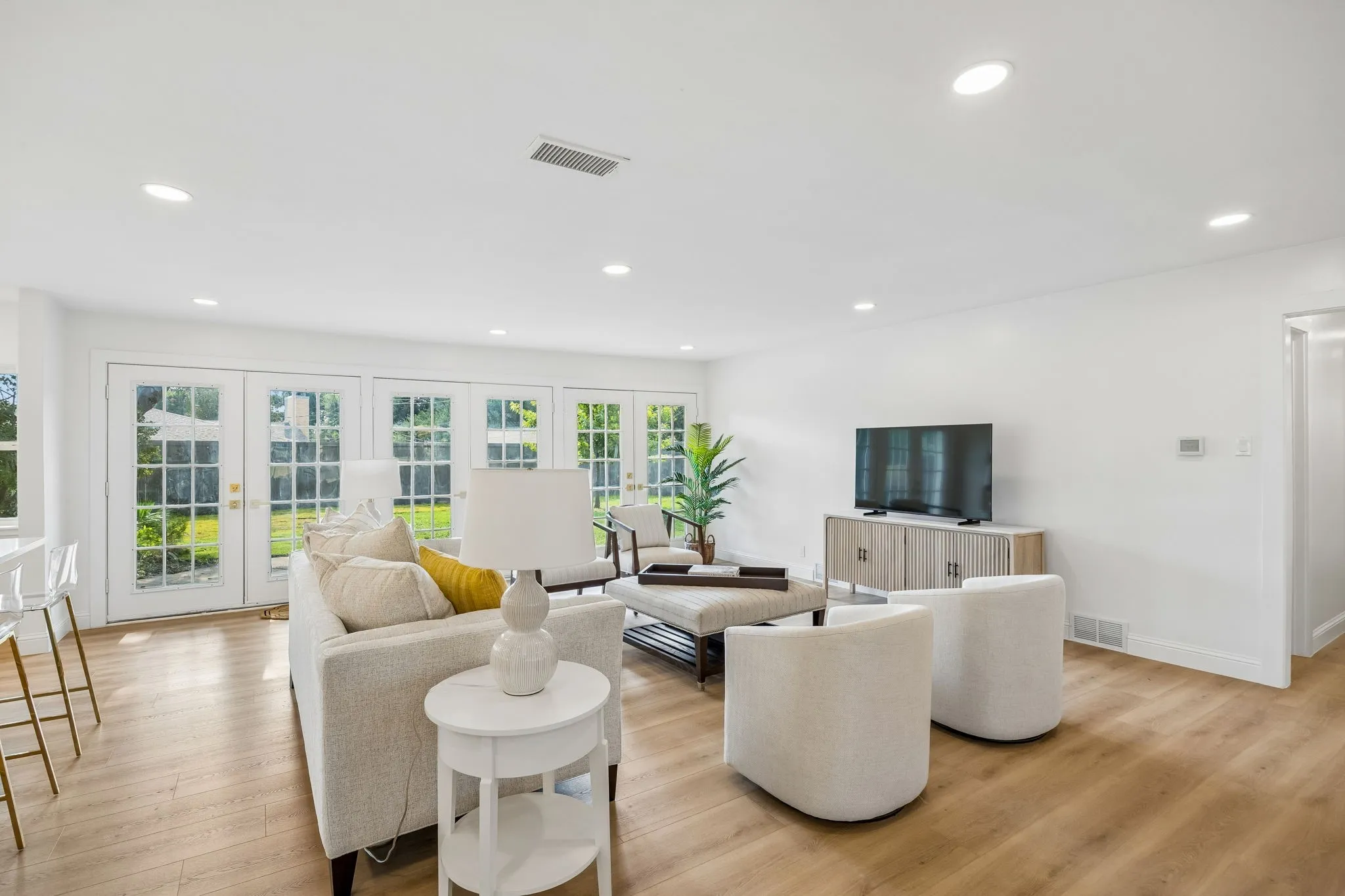 Spacious living area with LVT floors, recessed lighting and multiple French doors opening to the backyard.